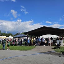 Outdoor community event with crowd and tents in Greene